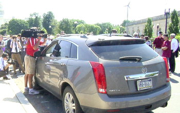 a driverless cadillac surrounded by people in front of Capitol Hill